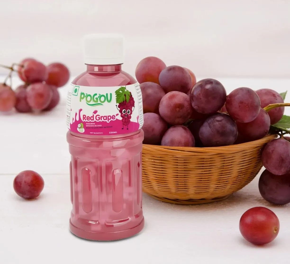 A bottle of Pogou Red Grape juice next to a basket of red grapes